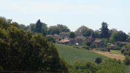 Vu du village de Reilhac, ancien chef lieu de la commune en 1806. La commune s'appelait alors Reilhac et Champniers. Au premier plan, on voit une haie, un peu plus loin, on distingue des champs.au fond, on voit le village de Reilhac.